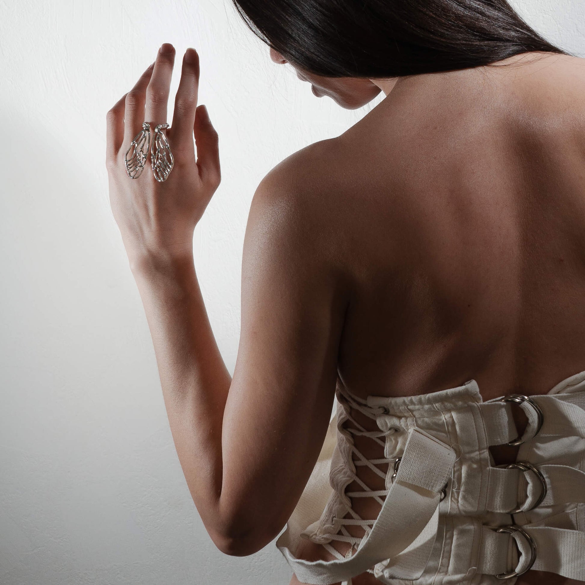 A woman wearing the Wings Ring, styled with a backless corset. The cicada-inspired design creates a striking statement, complementing the minimal yet bold look.